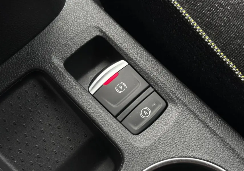 Gros plan sur les commandes du frein de parking électrique et auto-hold dans la console centrale noire du Renault Captur.