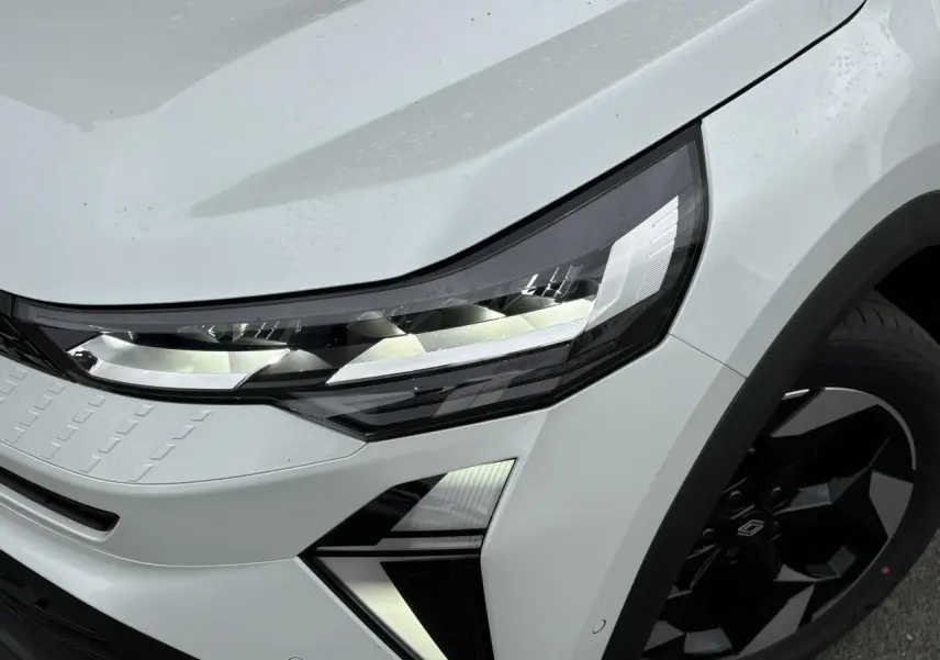 Gros plan sur l'avant droit du Renault Captur blanc nacré, mettant en valeur le phare LED Pure Vision et la jante noire.