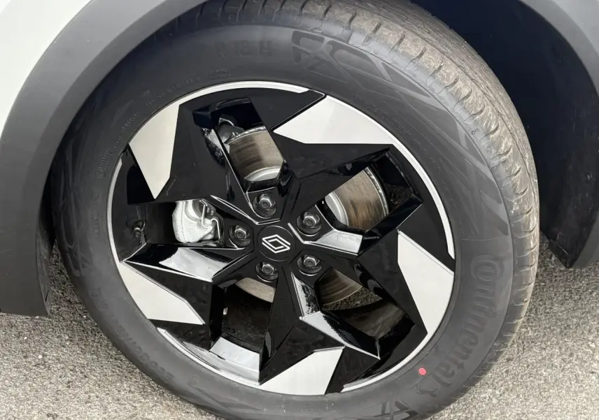 Gros plan sur la jante aluminium 18 pouces bicolore noire et argent du Renault Captur blanc nacré.