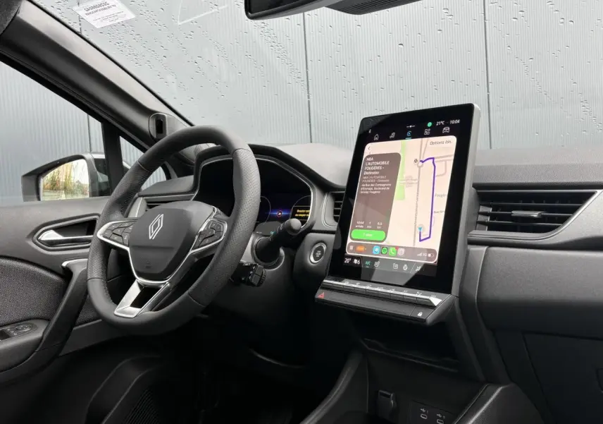 Vue intérieure côté conducteur du Renault Captur blanc nacré 2026, avec grand écran tactile vertical et volant multifonction.