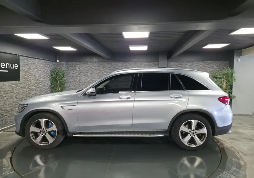 Vue de profil côté gauche d'un Mercedes GLC 350 e gris métallisé avec jantes alliage 19 pouces et marchepieds en acier.