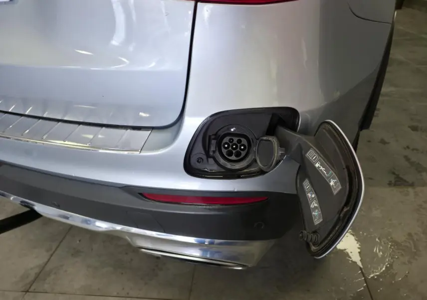 Détail de la prise de recharge ouverte à l'arrière droit du Mercedes GLC 350 e gris métallisé hybride rechargeable.