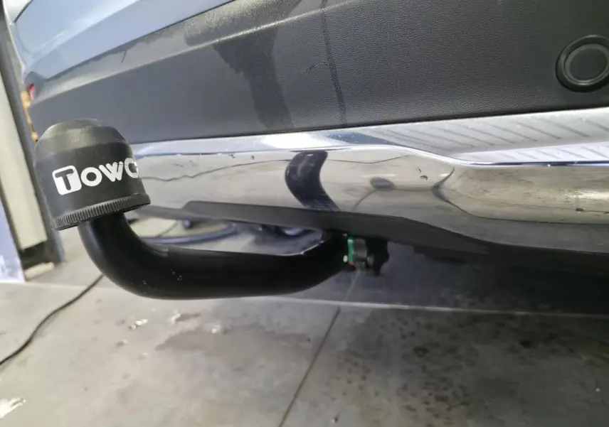 Gros plan sur l'attelage noir avec capuchon Towcar sous le pare-chocs arrière gris métallisé du Mercedes GLC.
