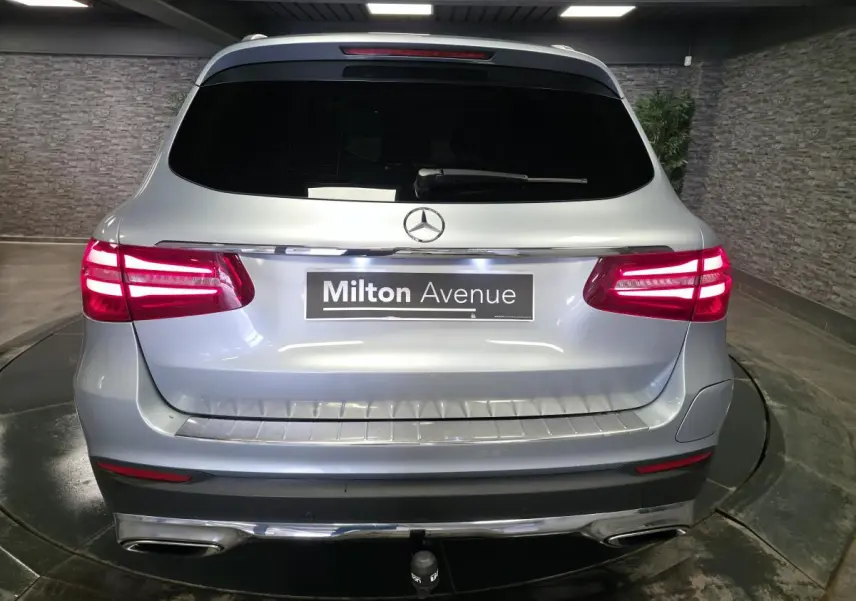 Vue arrière d'un Mercedes GLC 350 e gris métallisé avec feux LED allumés et attelage visible.
