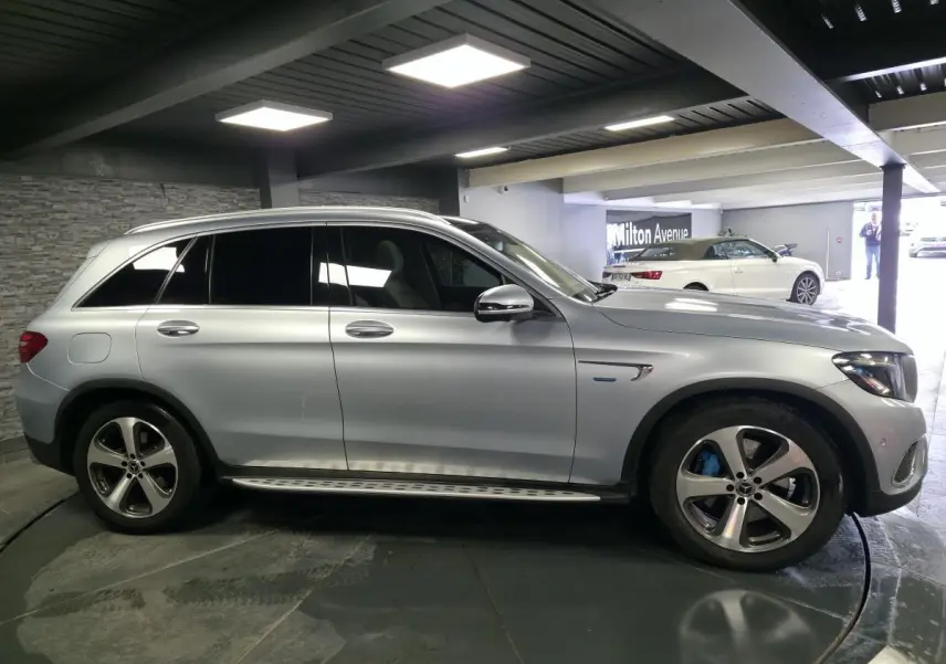 Vue de profil côté gauche d'un Mercedes GLC 350 e gris métallisé avec jantes alliage et marchepieds en acier.