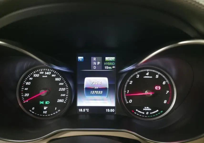 Vue rapprochée du combiné d'instruments numérique du Mercedes GLC 350 e gris, affichant mode hybride et compteur kilométrique.