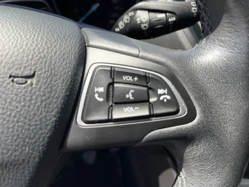 Gros plan sur les commandes audio au volant côté gauche du Ford Kuga 1.5 EcoBoost bleu foncé de 2018.