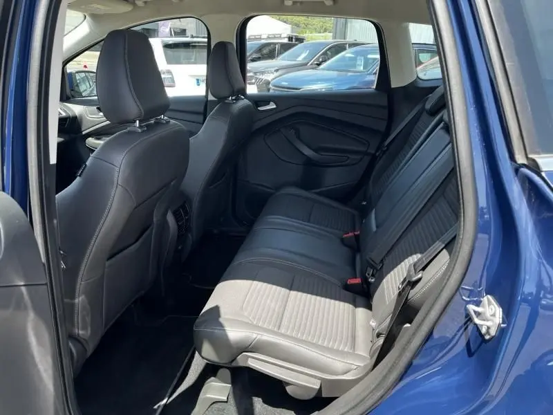 Intérieur arrière du Ford Kuga bleu foncé 2018, vue côté droit montrant les sièges en cuir noir et les ceintures de sécurité.