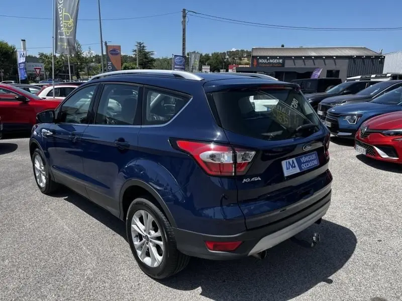 Ford Kuga 1.5 EcoBoost bleu foncé en 3/4 arrière droit, avec toit argenté et feux arrière distinctifs.