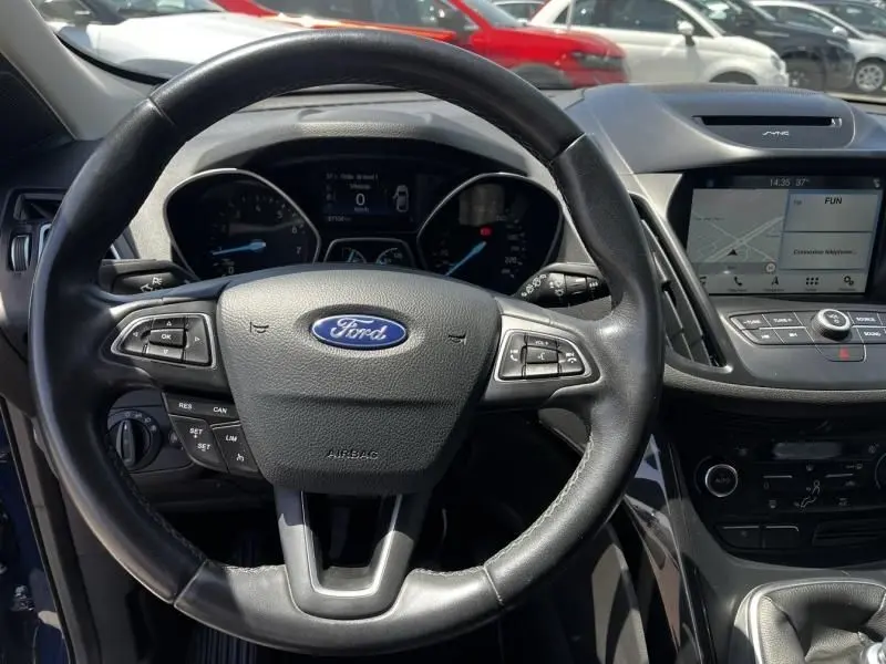 Vue intérieure centrée sur le volant noir du Ford Kuga 2018, avec tableau de bord et écran tactile visibles.