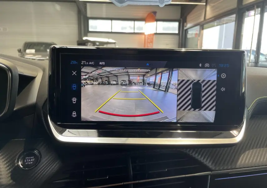 Écran central du Peugeot 2008 gris montrant la caméra de recul et l'affichage 360° dans un garage lumineux.