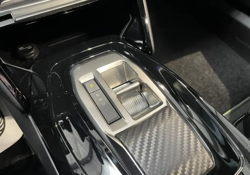Gros plan sur la console centrale du Peugeot 2008 gris 2026, mettant en valeur la commande de boîte automatique et le décor carbone.