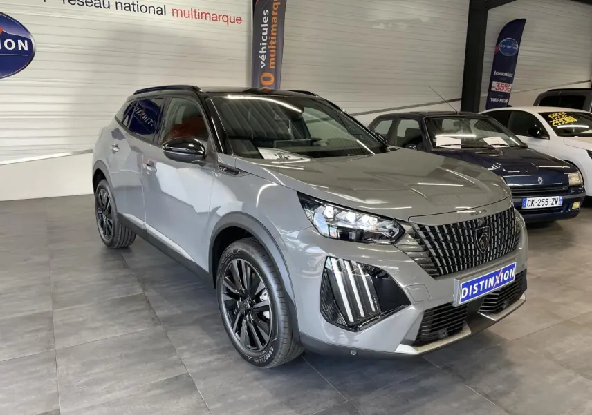Peugeot 2008 gris 3/4 avant droit en showroom, avec calandre noire et jantes alliage noires distinctives.
