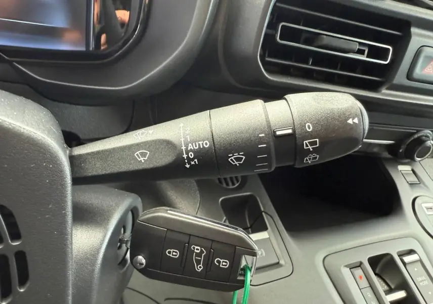 Gros plan sur la commande d’essuie-glace et la clé insérée dans le contacteur d’un Citroën Berlingo Fourgon blanc Icy.