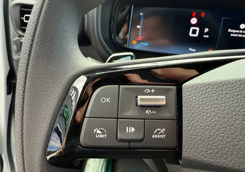 Gros plan sur les commandes au volant noir du Citroën Berlingo Fourgon XL Diesel 130ch, tableau de bord numérique en arrière-plan.