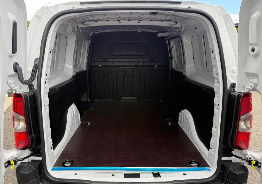 Vue arrière ouverte du Citroën Berlingo Fourgon XL blanc Icy, montrant l’espace de chargement vide et le plancher en bois.
