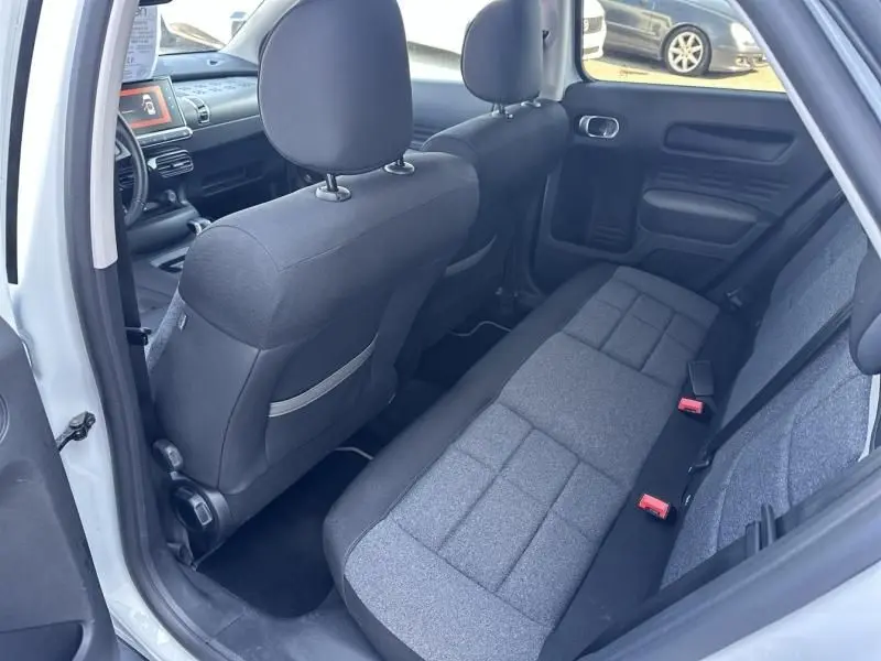 Intérieur arrière côté droit d'une Citroën C4 Cactus blanche 2018, sièges tissu gris et tableau de bord visible.