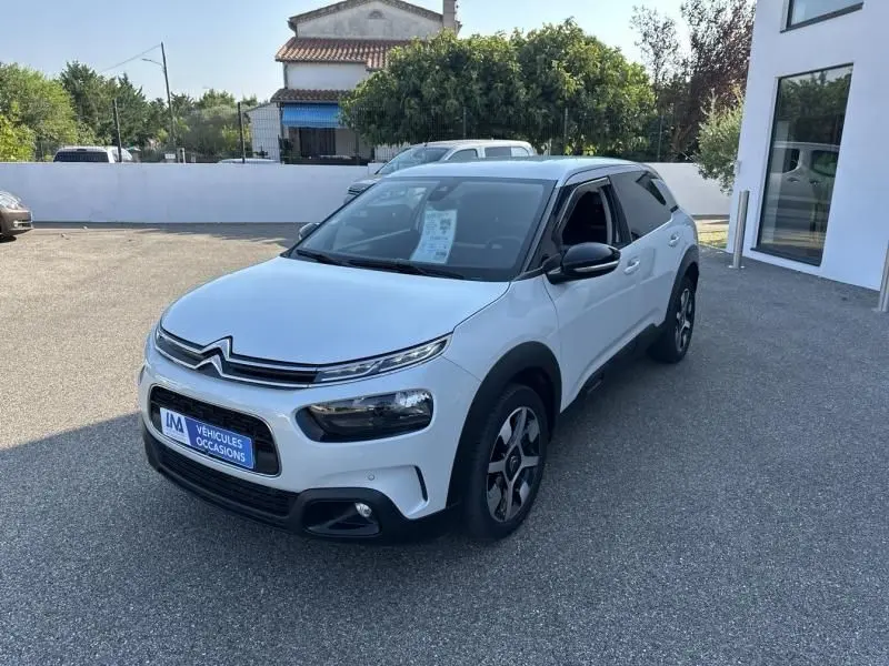 Citroën C4 Cactus blanc vue 3/4 avant droit, avec protections noires caractéristiques et jantes spécifiques.