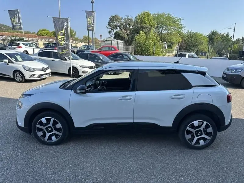 Profil côté gauche d'un Citroën C4 Cactus blanc 2018 avec jantes distinctives et vitres teintées noires.