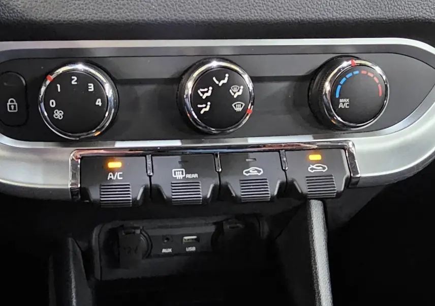 Détail du tableau de bord de la Kia Rio III 2015 montrant les commandes de climatisation et ventilation avec boutons rétroéclairés.