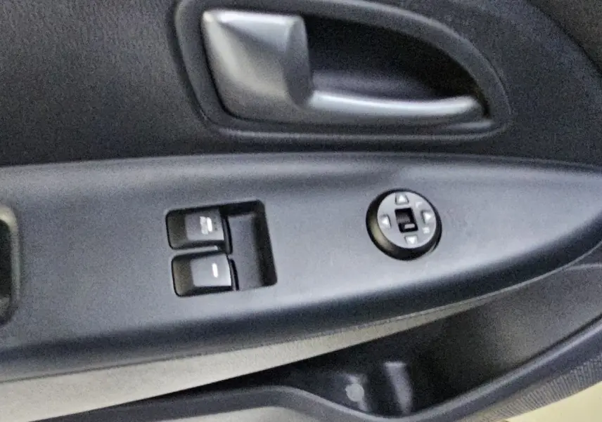 Poignée intérieure et commandes des vitres côté conducteur d'une Kia Rio III noire, version 3 portes de 2015.