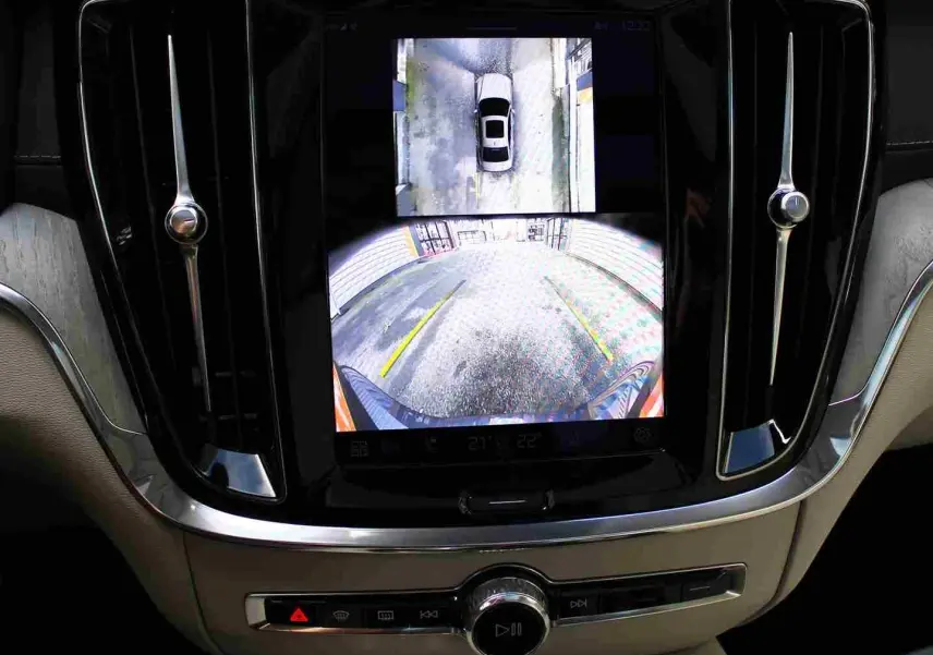 Écran central du Volvo S60 gris métal 2024 montrant la caméra de recul avec vue arrière et vue aérienne du véhicule.