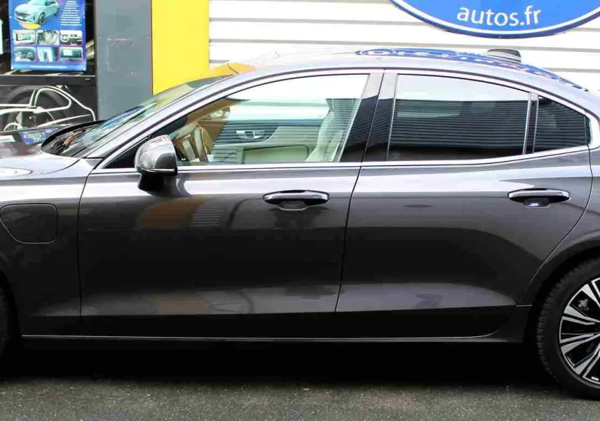 Profil côté gauche d'une Volvo S60 hybride rechargeable gris métal 2024 avec jantes alliage distinctives et lignes épurées.