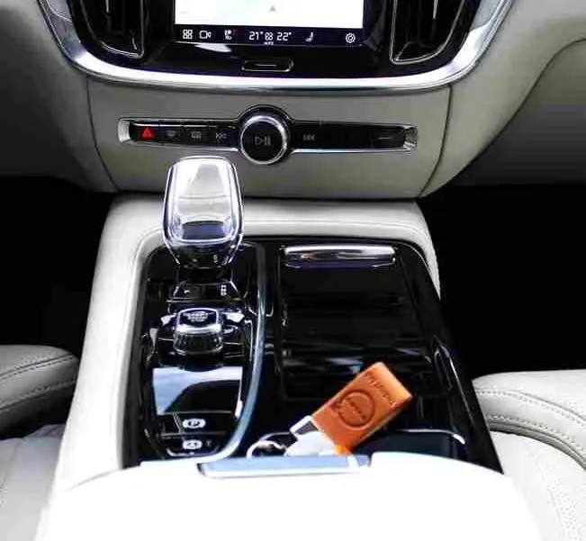 Vue rapprochée de la console centrale intérieure du Volvo S60 2024 avec écran tactile, levier de vitesses cristal et clé cuir.