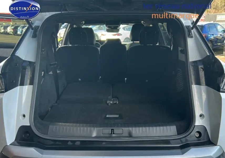 Coffre ouvert vu de l'arrière d'un Peugeot 5008 blanc okenite avec sièges arrière rabattus à plat.