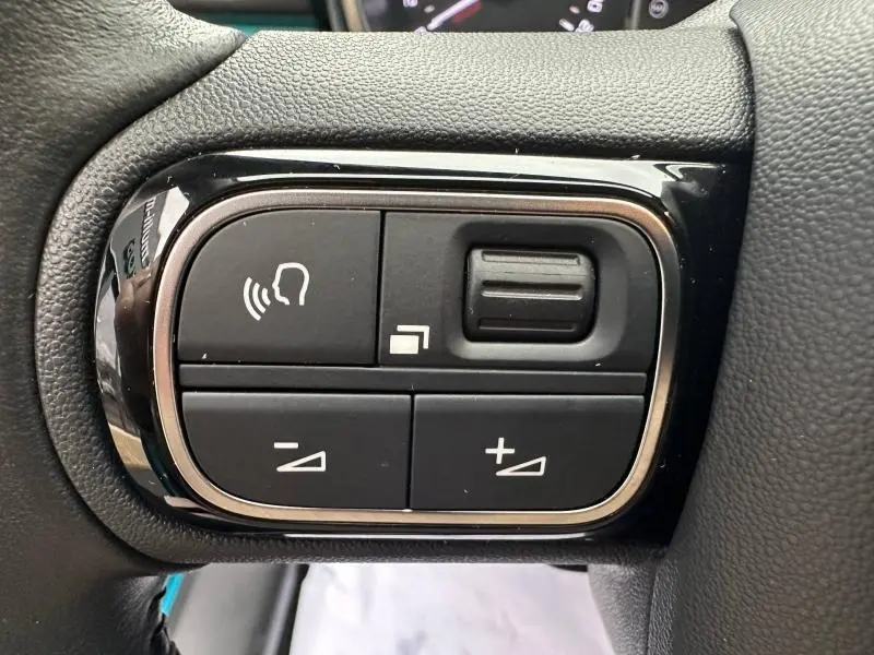 Gros plan sur les commandes noires du volant de la Citroën C3 2023, finition Spring Blue et Noir Perla Nera.