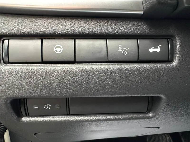 Gros plan sur les boutons de commande intérieurs noirs du Nissan Qashqai Hybrid e-POWER 2025, avec icônes blanches visibles.