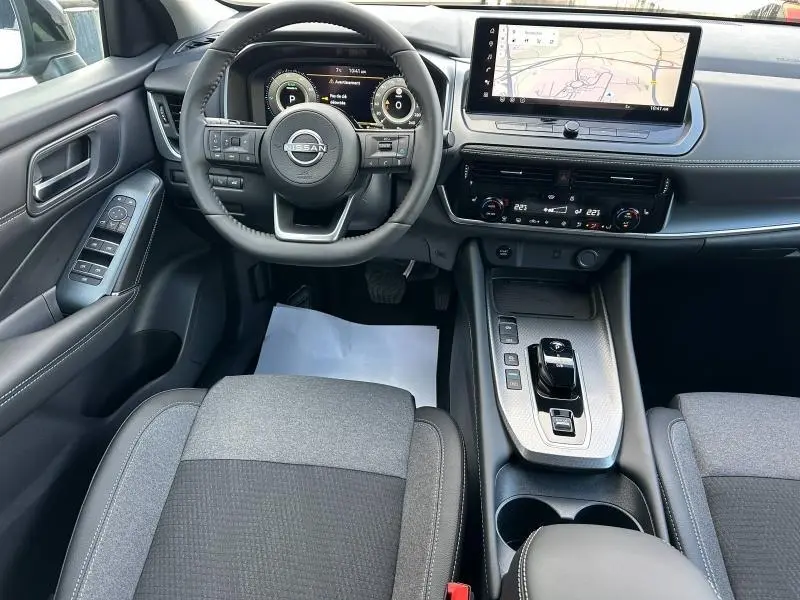 Vue intérieure du Nissan Qashqai Hybrid e-POWER 2025, tableau de bord moderne avec écran tactile et volant multifonction en cuir.