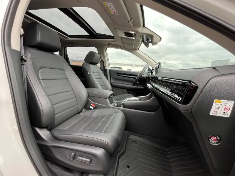 Vue intérieure côté droit du Honda CR-V 2024 blanc, sièges cuir noir, toit panoramique et tableau de bord moderne.