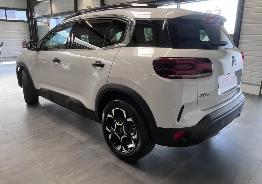 Vue 3/4 arrière droite d’un Citroën C5 Aircross blanc nacré avec jantes alliage bi-ton et vitres surteintées.