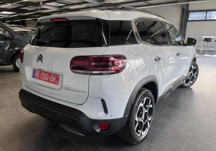 Vue 3/4 arrière droit d'un Citroën C5 Aircross blanc nacré avec jantes alliage bi-ton et vitres teintées.