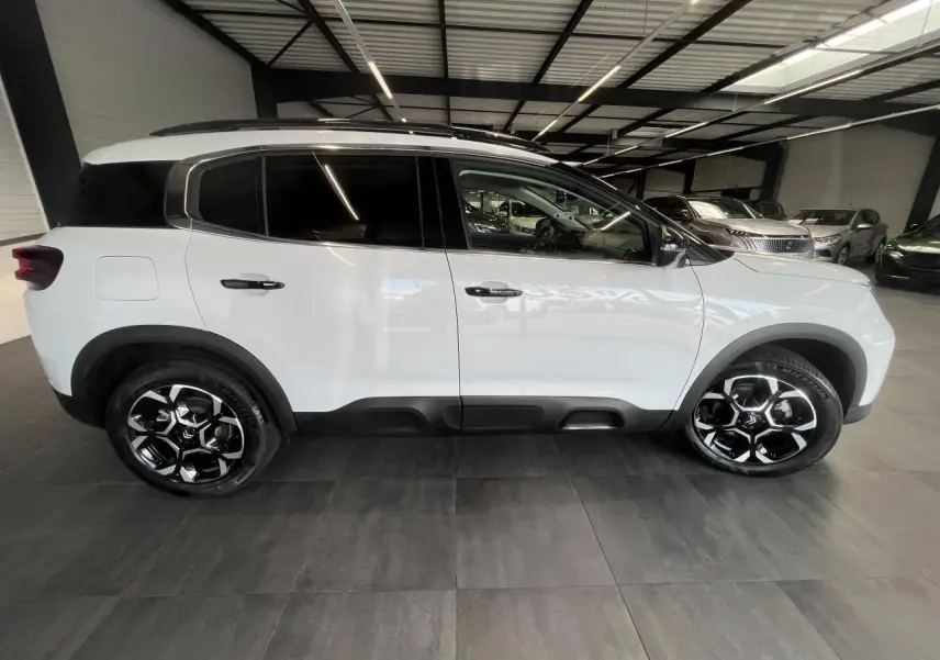 Vue de profil côté gauche d'un Citroën C5 Aircross blanc nacré avec jantes alliage bi-ton et vitres surteintées.