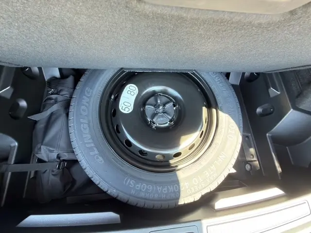 Vue rapprochée de la roue de secours noire dans le coffre du Renault Austral 2025 noir, version hybride E-Tech.