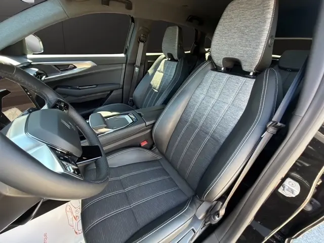 Vue intérieure côté conducteur du Renault Austral noir 2025, sièges tissu et cuir gris avec volant multifonctions en cuir.