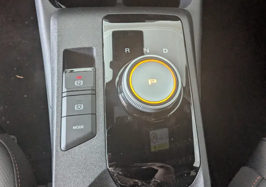 Gros plan sur la molette de boîte automatique et les boutons de contrôle du MG3 1.5L Hybrid+ 2026, finition noire.