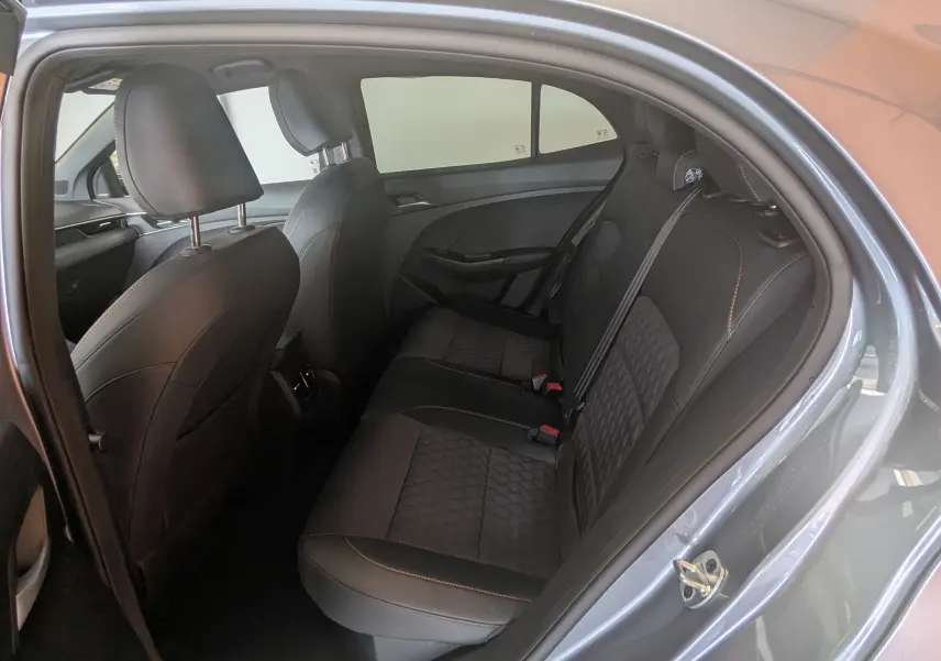 Vue intérieure côté droit des sièges arrière en cuir noir avec surpiqûres orange d’un MG3 1.5L Hybrid+ 2026 gris métallisé.