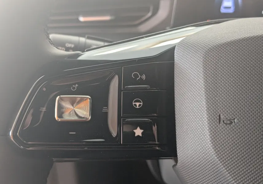 Gros plan sur les commandes noires à gauche du volant gris texturé du MG3 1.5L HYBRID+ 195CH LUXURY 2026.