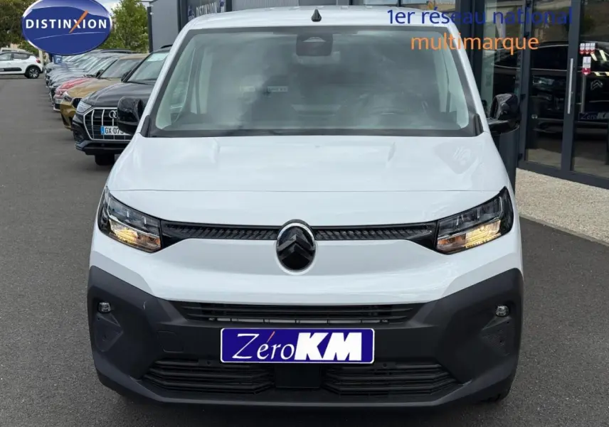 Vue frontale d'un Citroën Berlingo Fourgon XL Diesel 130ch blanc Icy avec phares allumés sur parking extérieur.