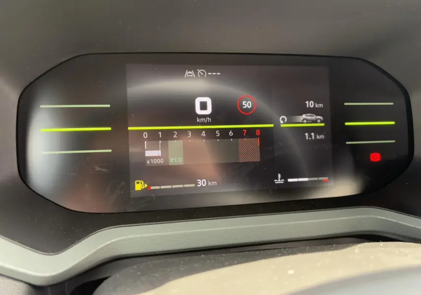 Tableau de bord digital du Dacia Duster 2025 affichant vitesse, régime moteur et autonomie, vue frontale intérieure.