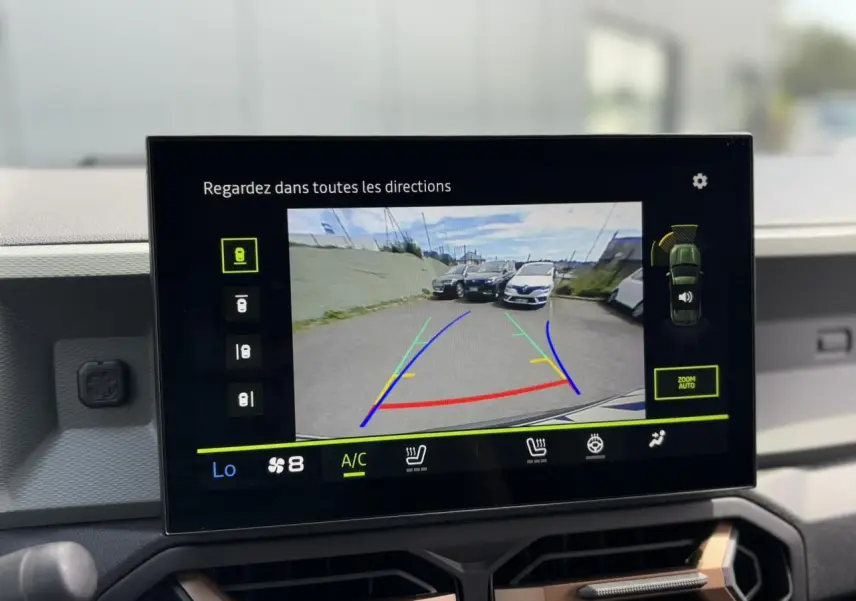Écran tactile affichant la caméra de recul du Dacia Duster gris schiste avec lignes de guidage colorées.
