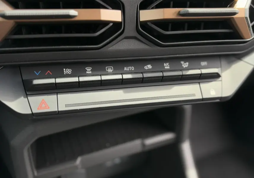 Détail de la console centrale du Dacia Duster 2025 avec commandes climatisation et bouton de verrouillage