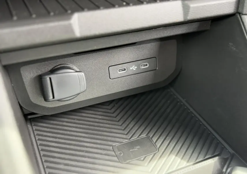 Gros plan sur la console centrale du Dacia Duster 2025 gris avec ports USB-C et zone de charge sans fil.