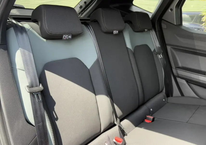 Vue latérale des sièges arrière gris clair et noir du Dacia Duster 2025 avec ceintures de sécurité visibles.