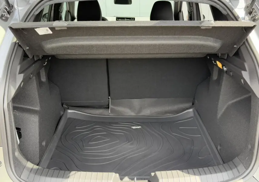 Coffre ouvert du Dacia Duster 2025 gris schiste, montrant le tapis de coffre noir et l'espace de rangement intérieur.