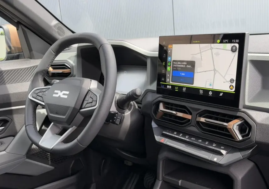 Vue intérieure du tableau de bord du Dacia Duster 2025 avec écran tactile GPS 10 pouces et volant multifonction noir.