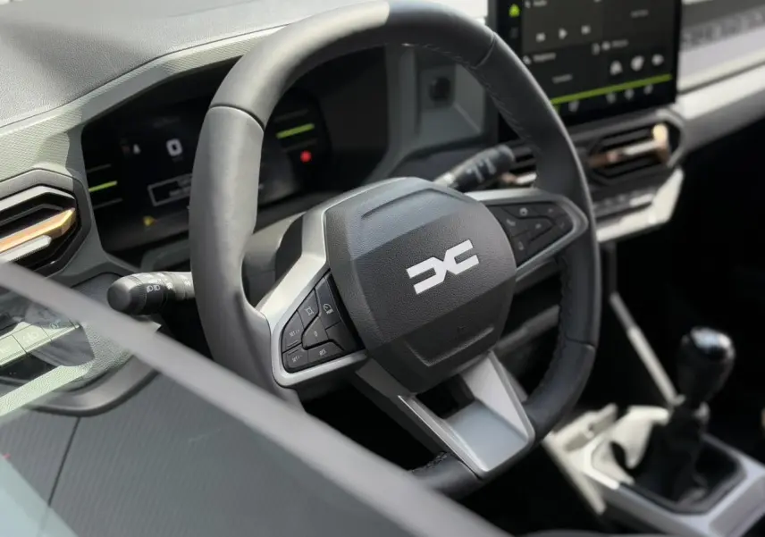 Gros plan sur le volant multifonction noir et la console centrale du Dacia Duster TCE 4X2 2025.
